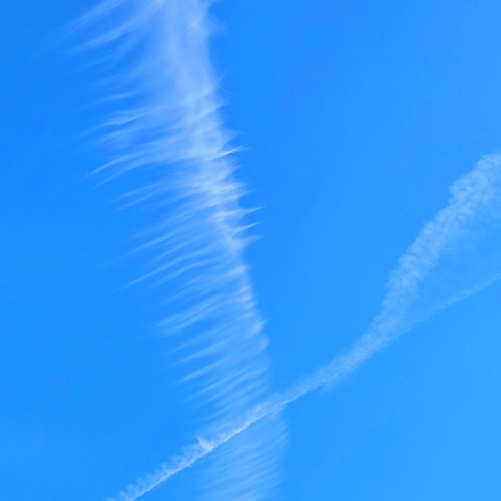 Fedrige Wolke gekreuzt von Kondensstreifen.