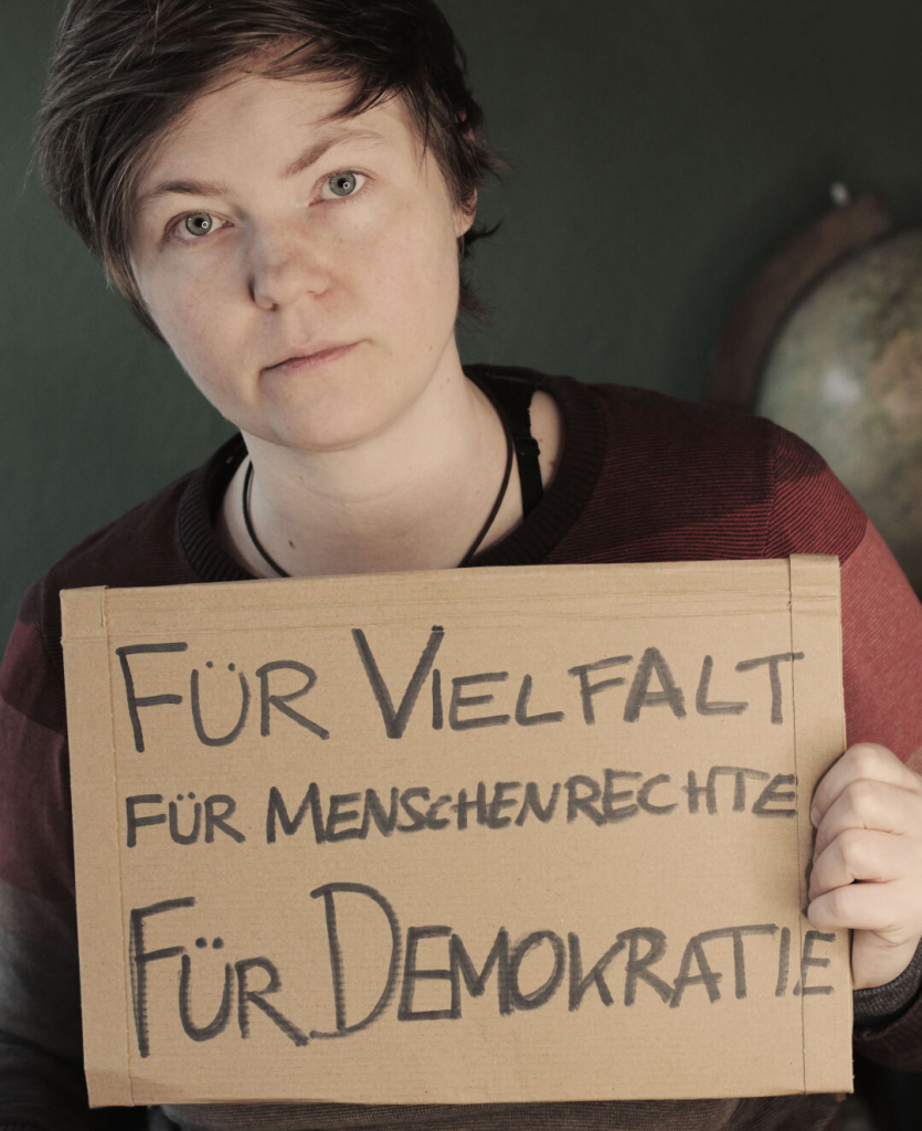 Das ist ein Foto von mir mit einem Demoschild.
Darauf steht:
"Für Vielfalt
Für Menschenrechte
Für Demokratie"

Ich habe es für die Demo "Licht an! Für Demokratie" gebastelt, die vor einen Wochen hier in Leipzig stattgefunden hat. Es war sehr schön dort.