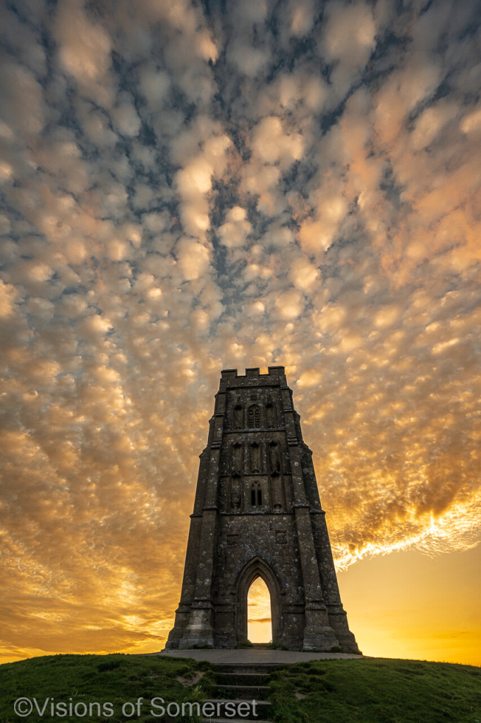 Golden sky behind the tower. Bubble type clouds in the sky throughout the scene. 