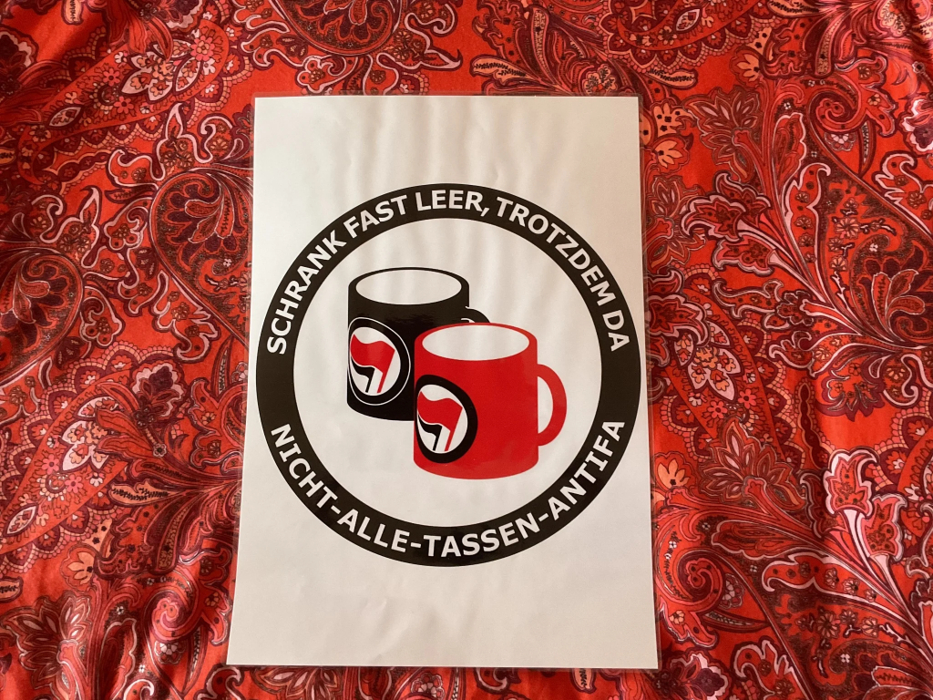 Großer AntifaSticker mit „Schrank fast leer, trotzdem da - Nicht-alle-Tassen-Antifa“, rund und mit zwei Bechern in der Mitte mit Antifa-Flaggen