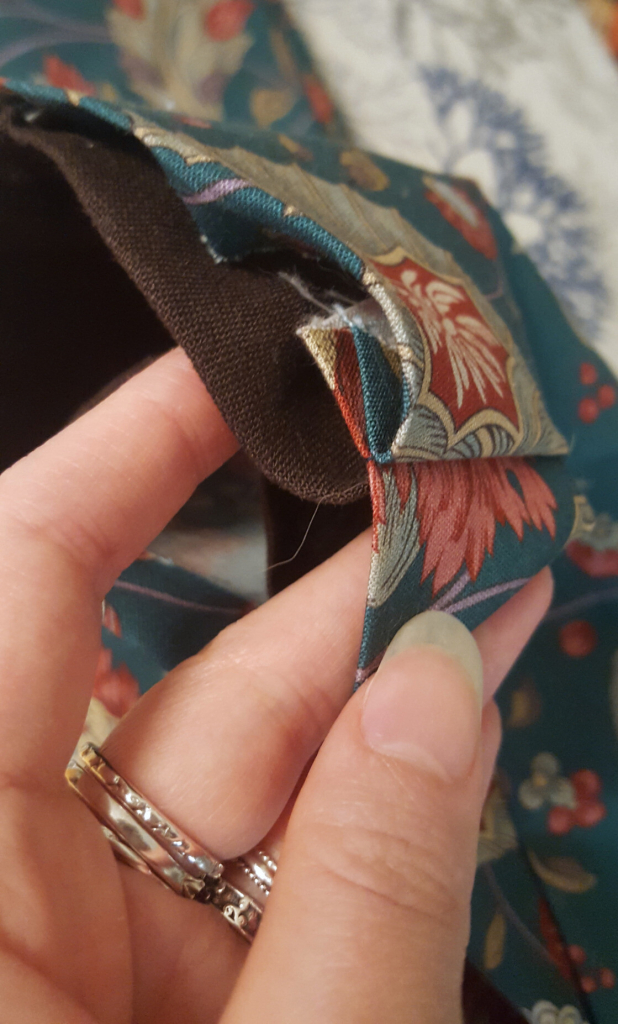 A photo of the cuff, looking inside the as of yet sewn shut outer and lining layers. The seam allowances are all within the two layers, all on one side of the seam. The cuff edges are the ironed single fold of fabric, and when sewn down, every raw edge will be hidden.