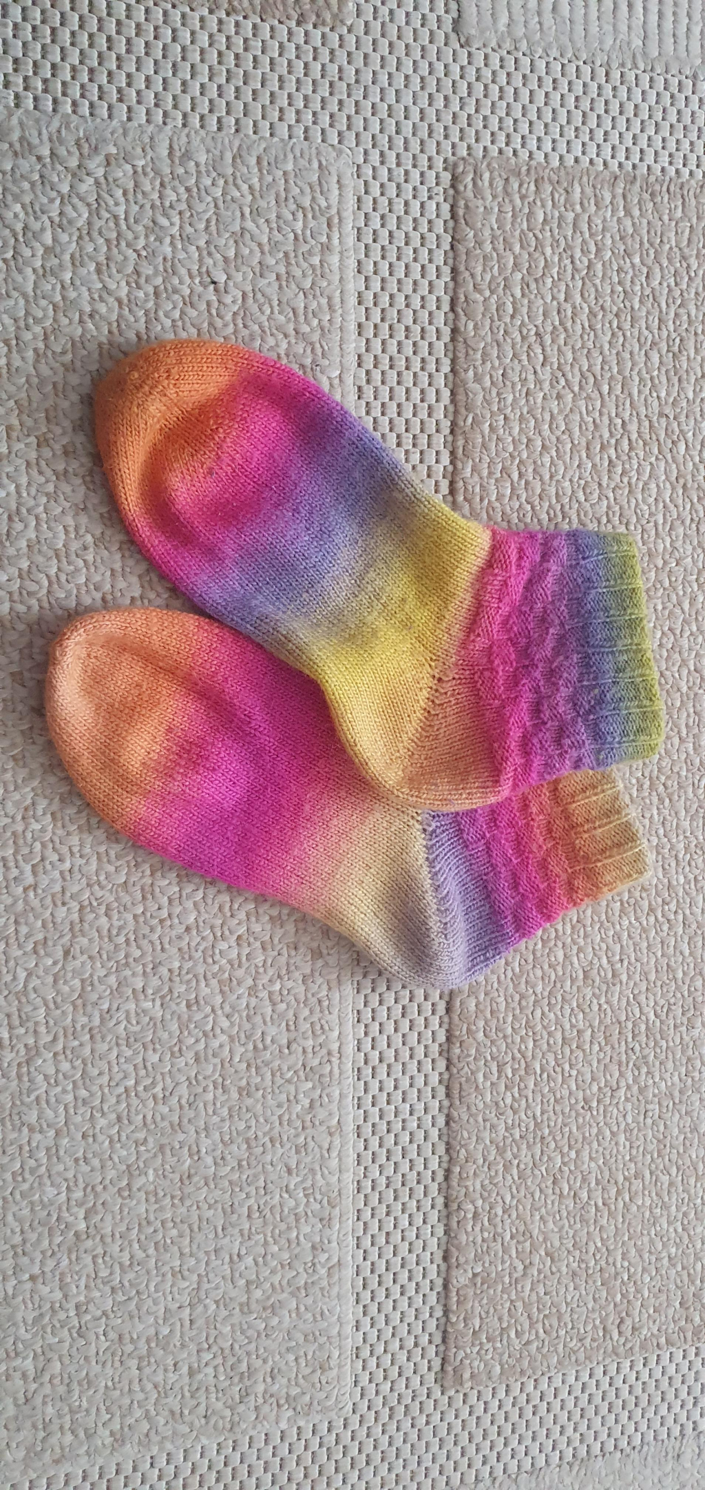 Handgestricktes Paar Socken in Regenbogenfarben