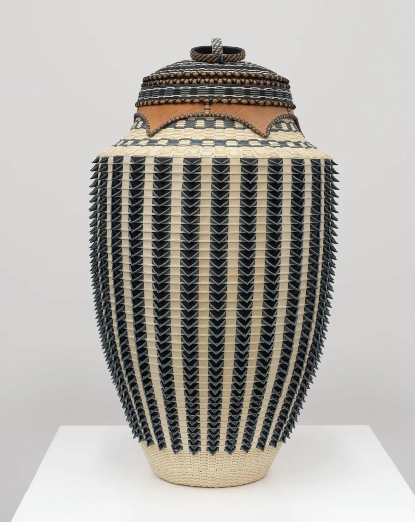 Tall, oblong basket with a 3D vertical line pattern of black and cream, with a pale cream border bottom and several thin patterned horizontal lines along the top for the lid.