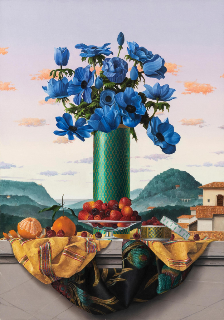 Still life painting in a photorealistic style depicting an tall green vase holding an assortment of blue flowers, surrounded by various fruits and a draped patterned silk textile. The tableau is set on a white balcony edge with a green hilly landscape with houses in the background, and a purple/orange/green gradient sky.