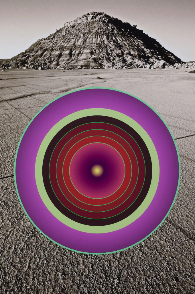 Black and white photo of a desert expanse with a rocky peak in the background. Over the scene floats a large circle with several concentric circles in purple, green, and maroon in various layers.