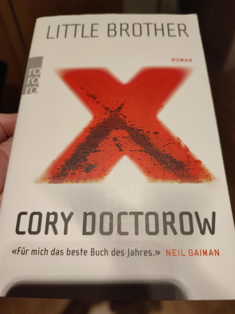 Das Foto zeigt das Buchcover von Cory Doctorows "Little Brother". Ein großes, rites X prangt in der Mitte. "Für mich das beste Buch des Jahres.", nannte es Neil Gaiman.