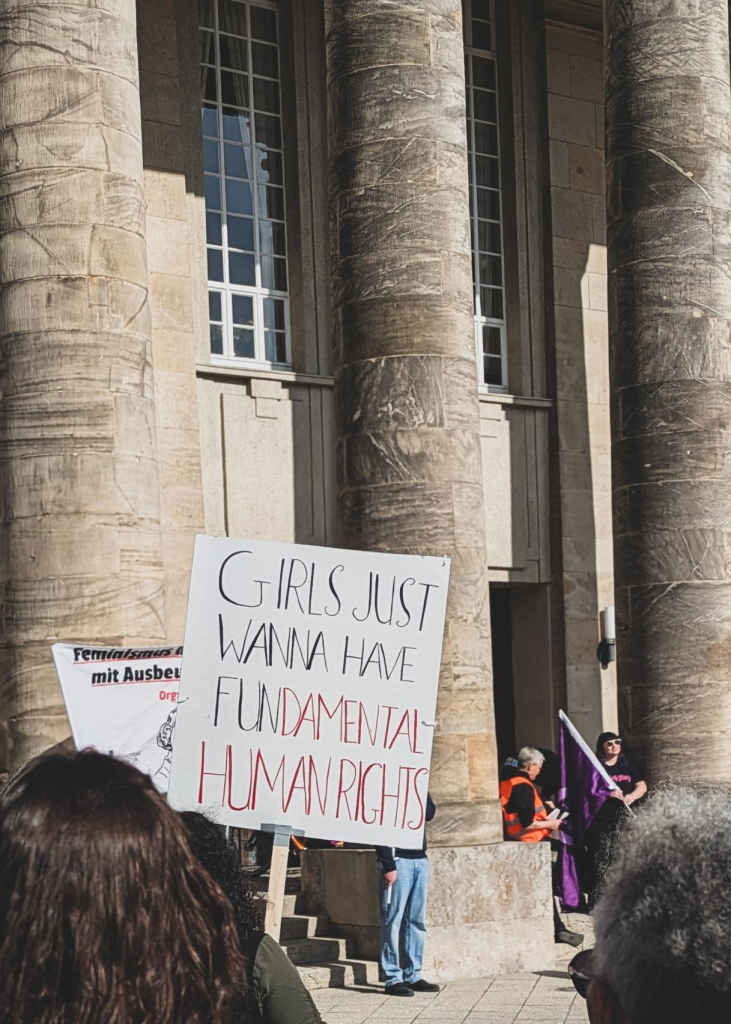 Der Theatervorplatz in Detmold,  Vordergrund ein Demoplakat mit der Aufschrift "Girls just wanna have fundamental human rights"