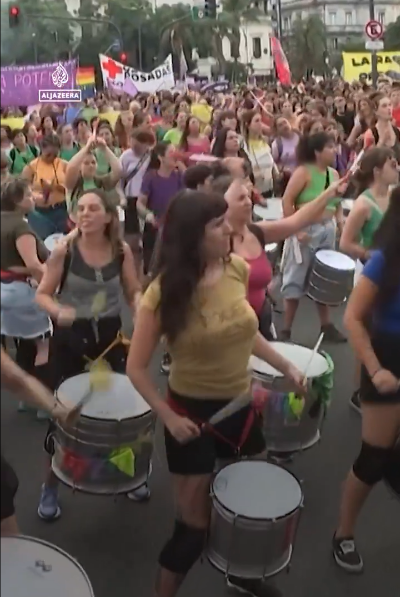 Thousands of protesters with flags and placards, led by drummers in the streets of Buenos Aires