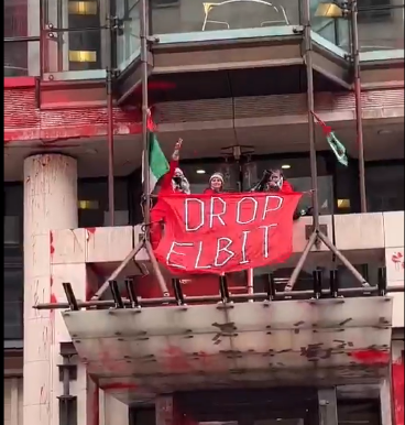 Three Palestine actionists chained to the scaffolding of the Allianz building with Palesitnian flags, holding a banner reading DROP ELBIT