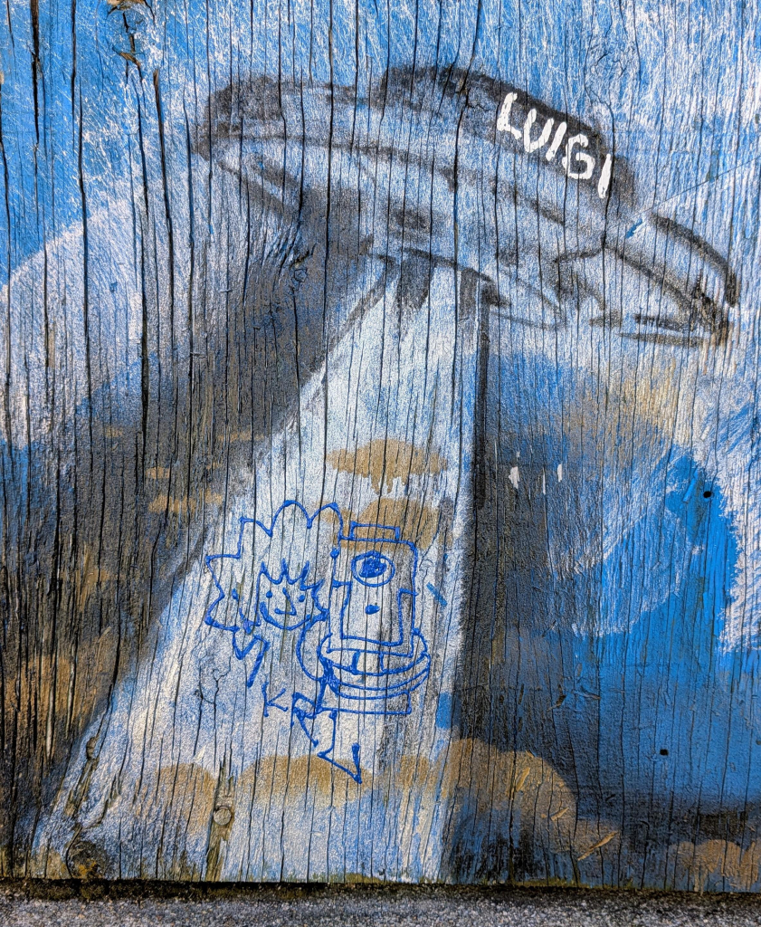 Graffiti showing a flying saucer above a person pointing a pistol at the viewer. The space craft appears to be "beaming up" the shooter.