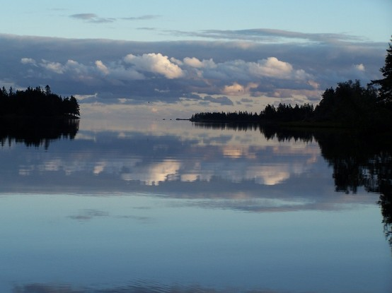 Looking out the harbour, the ocean is smooth as far as you can see.. Trees on the shorelines on either side, clouds mirroring off the surface. Calming