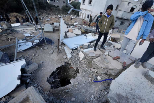 Palestinians look at the building of the Darwesh family, killed in the Israeli bombardment of the Gaza Strip, in Nusseirat refugee camp, central Gaza. Photograph: Adel Hana/AP