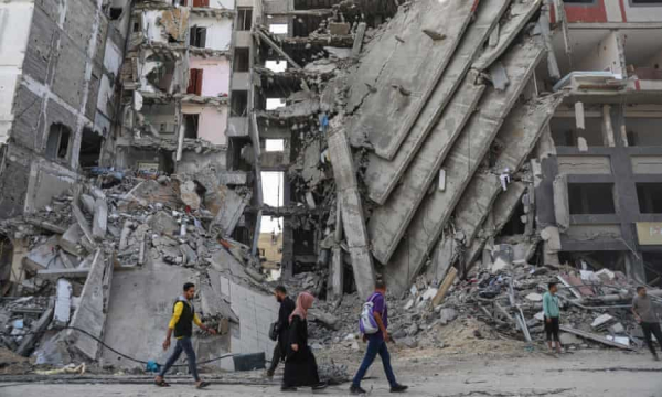 Palestinians walk past destroyed buildings in Gaza City on Friday as the temporary ceasefire took effect. Photograph: Mohammed Hajjar/AP