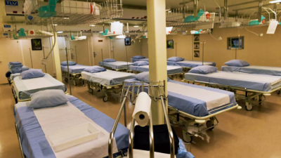 The image depicts a large hospital room filled with numerous beds. The beds are arranged in rows, with some positioned closer to the foreground and others further back in the room. The room appears to be a ward or a dormitory-style setting, designed to accommodate multiple patients.