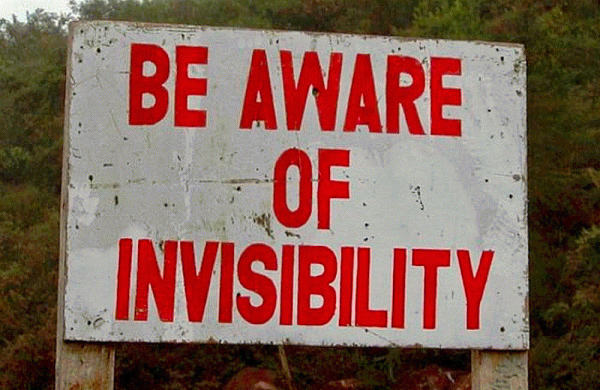 a distressed white sign with bold red text that says: "Be aware of invisibility."