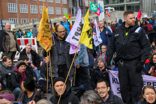 Aktivist verteilt Fahnen bei der Besetzung der Elsenbrücke für den Abbau fossiler Subventionen durch verschiedene Klimagruppen. Berlin, 02.03.2024