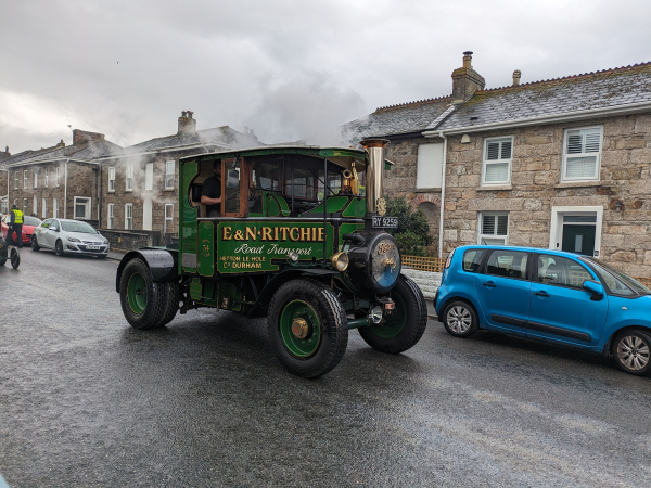 A steam lorry driving down a street. 