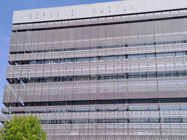 Front facade of the Museum of Ethnography in Budapest, decorated with a metal lace pattern of cross stitch motifs.