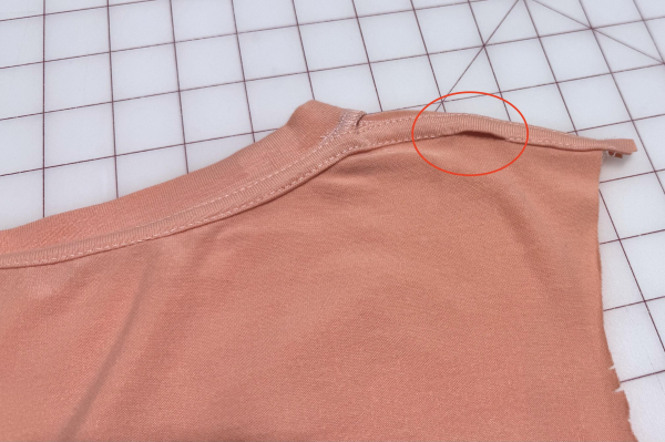 A peach t-shirt with binding sewn on the collar; you can see that the binding was missed right before the end on the right-hand side.