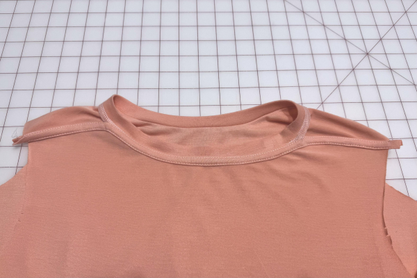 Interior rear view of a peach t-shirt with binding sewn on the collar after a successful second pass.