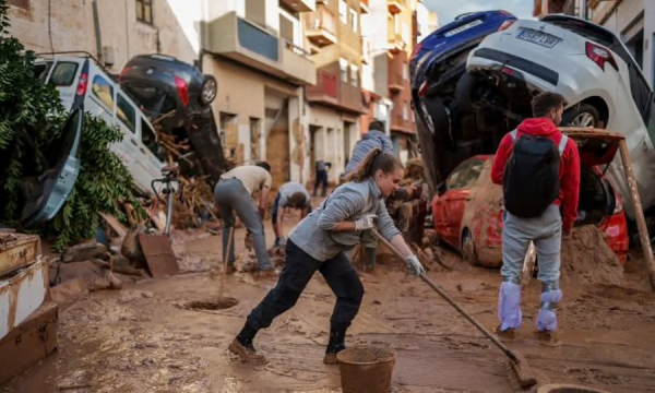 Picture: woman tries to clean up the mud and what remains of the flood in Spain.