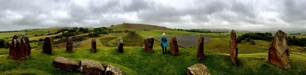 A figure stands amongst some of the stones at Crawick looking towards more of the sculptures