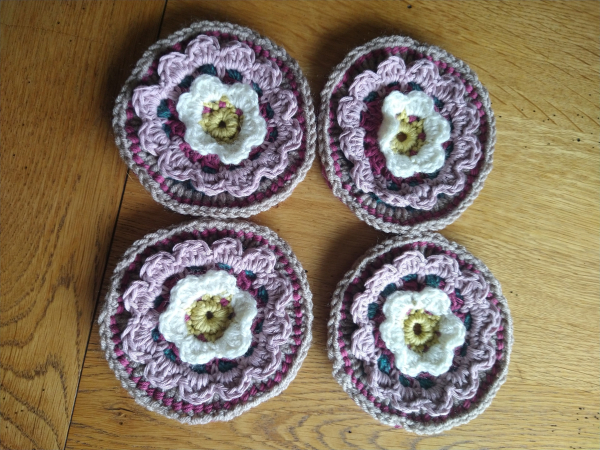 Four Circular crochet motifs, with a yellow and white flower design at the centre 