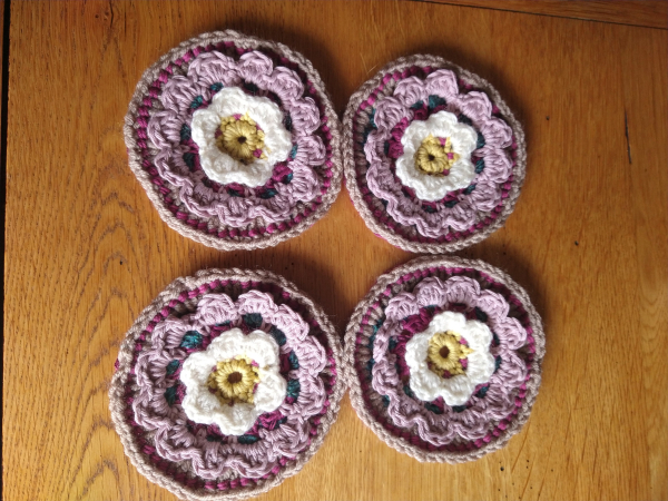 Four Circular crochet motifs, with a yellow and white flower design at the centre and pink outside pattern 