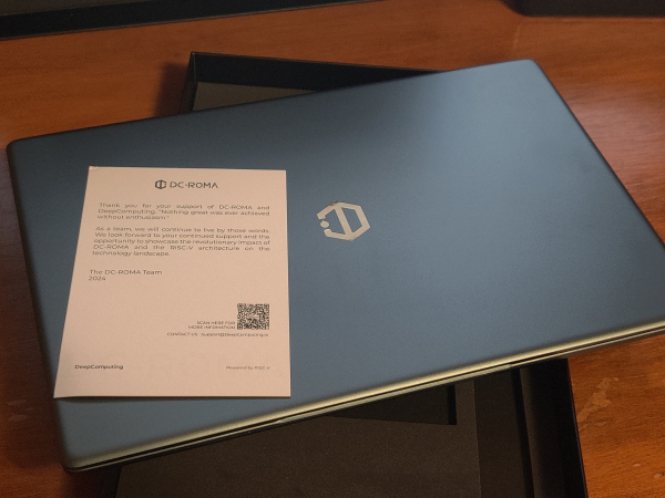 A thin laptop with DeepComputing logo resting on its box. There's a small slip of paper with a Thank You note. 