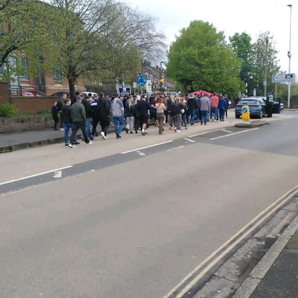 The tail end of the same march, showing what I'd estimate to be 50-60 people. There is a police car parked on the corner nearby and they are being watched by a single police officer, but his pose is casual and he doesn't look particularly concerned 