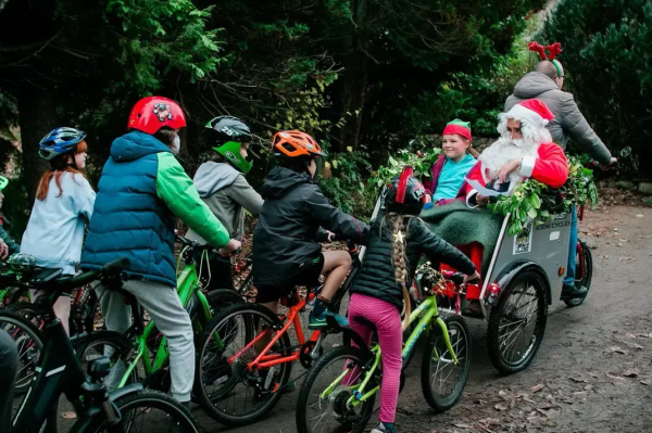 A pack of children on bikes being led by a bloke wearing reindeer horns pulling a bike trailer set up as Santa's sleight and possibly regretting his life choices slightly. In the sleigh/trailer is a man dressed as Santa and a small boy dressed as an elf