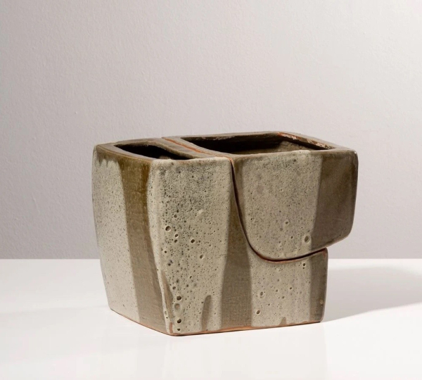 Ceramic vase in a loose cube shape with two openings and cream and light brown glaze