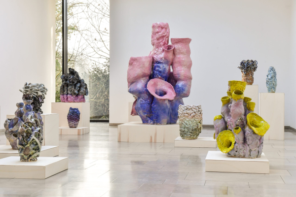 Several large, colorful abstract ceramic sculptures arranged on white pedestals in a gallery