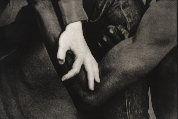 Black and white photo of a white hand and black arm embracing, in close-up