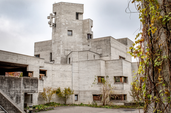 Photo of a Brutalist-style concrete church with harsh corner and a central tower with a flat roof and square windows