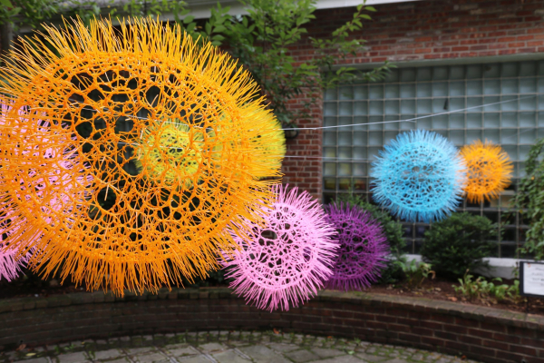 Hanging spiky orbs in various colors installed in a brick courtyard