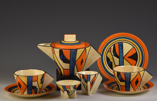 Brightly painted ceramic tea set with sharp geometric shapes and painted geometric patterns in orange, yellow, and blue 