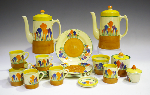 Brightly painted ceramic tea set with a soft yellow background and cheery painted flowers above a bronze base