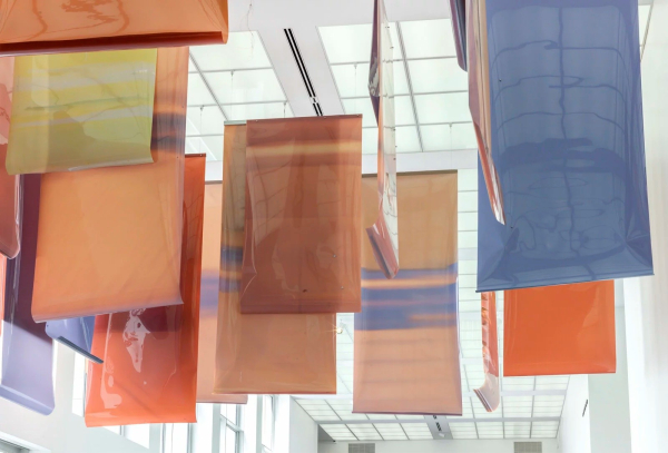 Long strips of large-scale photographic film handing from the ceiling, with different colors and soft abstract shapes