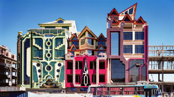 Cluster of three colorful, playfully designed buildings with geometric motifs including circles, steps, and snakes, with angled roofs and a mixture of textures