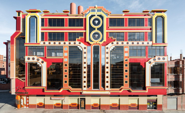 A large horizontal building with bold geometric facade in red, yellow, white, and orange colors. The symmetrical design features curved borders and circle patterns.