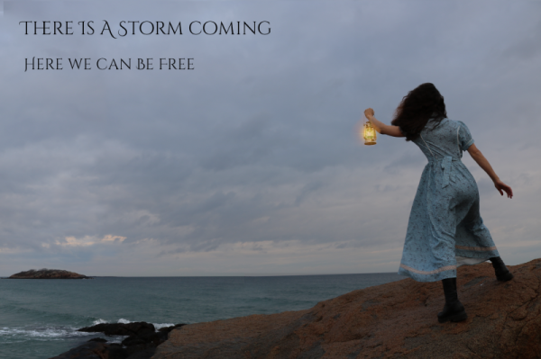 A woman in a 19th century dress holds out a lantern to stormy skies gathering over Salt Island, Massachusetts