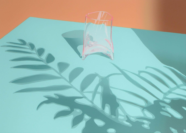 Print of a small pink glass vessel sitting on a mint green table, with shadows of leaves falling across the surface