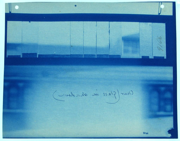 Blue-tinted photo of a glass panel seen from the back with writing "Clear (glass in shadow)" visible backwards