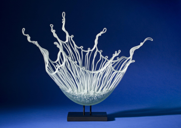 Glass sculpture of white wavy lines collecting together at the bottom, resembling a plop of water exploding upward after something's been dropped into it