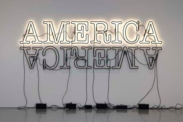 A neon sign with the text "AMERICA" written twice: One is right-side up and lit up white, the other is underneath it, flipped upside down and reversed, and unlit