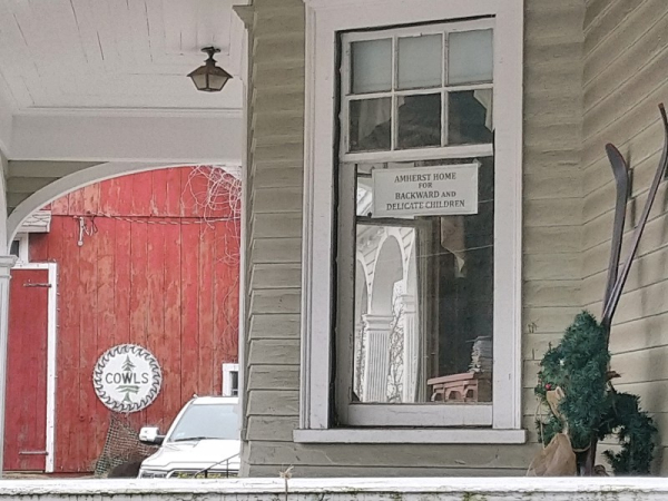 A traditional house with a window sign that reads "Amherst home for backward and delicate children."