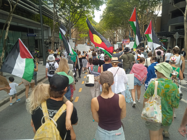 People marching with Palestinian and aboriginal flags