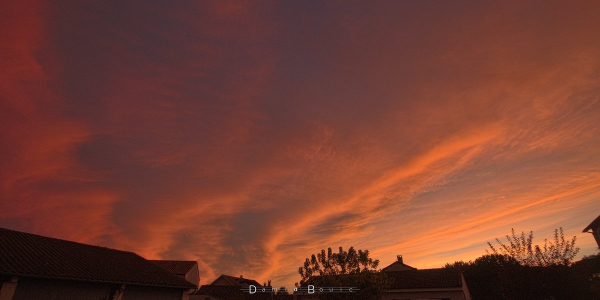 Ciel crépusculaire aux couleurs rouges intenses dues aux nuages d'altitude qui sont illuminés par en dessous, reflétant les lueurs cuivrées du Soleil couchant