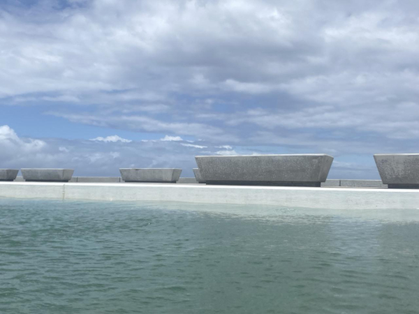 Several benches sit beside the grey green waters of the Ocean Baths supporting white fluffy clouds. The benches are long, flat and solid; they make me think of neolithic altar slabs. 